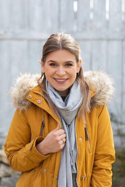 Portrait of an attractive young woman wearing yellow parka jacket outdoor - Foto, immagini