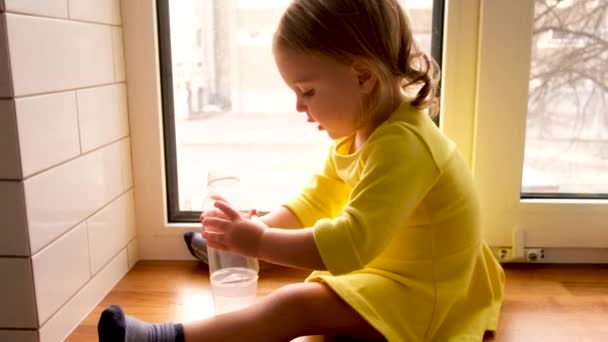 Spokojna dziewczynka z butelką wody w domu - Materiał filmowy, wideo