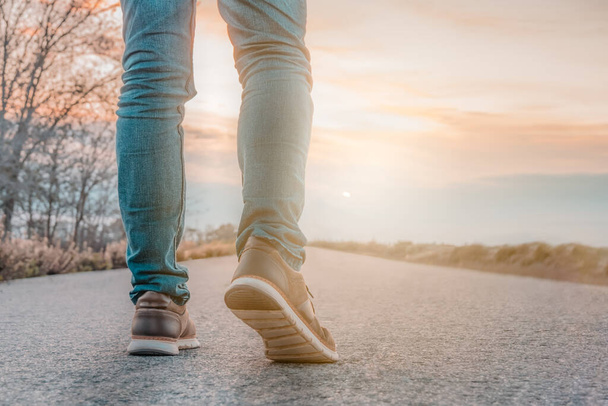 Güneşli yolda yürüyen bir adam. Kotlu ve kahverengi ayakkabılı bir adamın bacakları kapalı. Seçici odak - Fotoğraf, Görsel