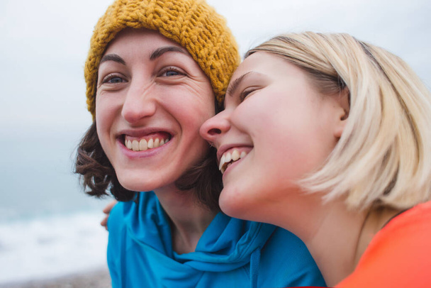 Happy gay couple having fun together outdoor. Young women having a date. Equality right, homosexuality lifestyle, lgbt, and relationship concept. Two smiling girls hug each other on the beach. - Photo, Image