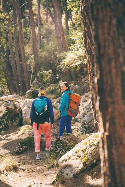 Δύο κορίτσια περπατούν στο δάσος. Πεζοπορία στα βουνά. Οι φίλες περνάνε χρόνο μαζί στη φύση. Οι γυναίκες περπατούν στο πάρκο. - Φωτογραφία, εικόνα