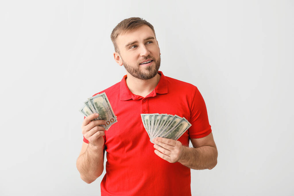 Handsome young man with money on light background - Fotografie, Obrázek