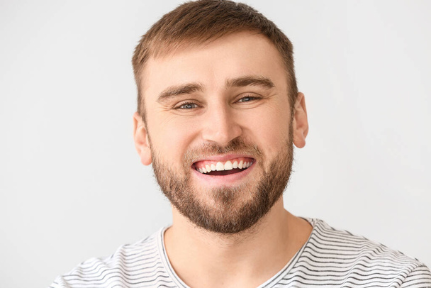 Lächelnder junger Mann auf hellem Hintergrund - Foto, Bild