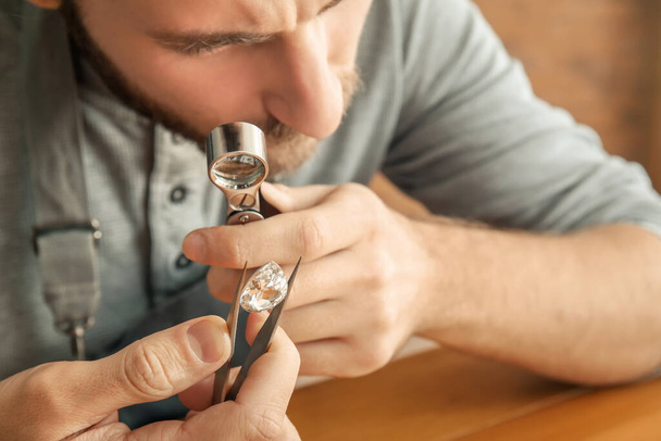 Jeweler examining gemstone in workshop - 写真・画像