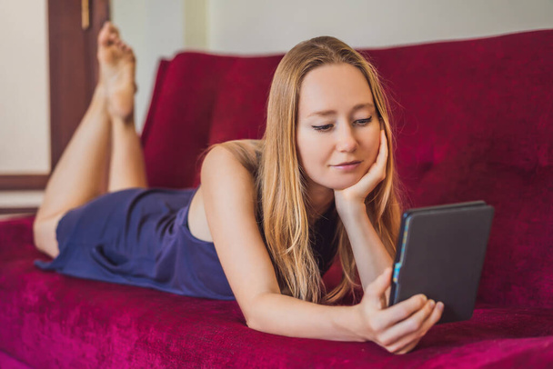 Young woman reads e-book at home on the couch - Photo, image