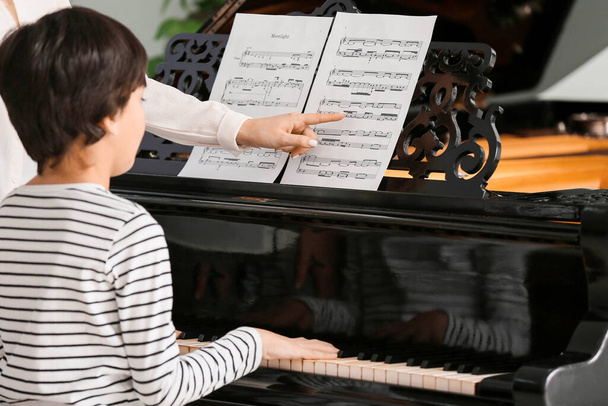 Ιδιωτικός δάσκαλος μουσικής δίνει μαθήματα πιάνου σε μικρό αγόρι - Φωτογραφία, εικόνα