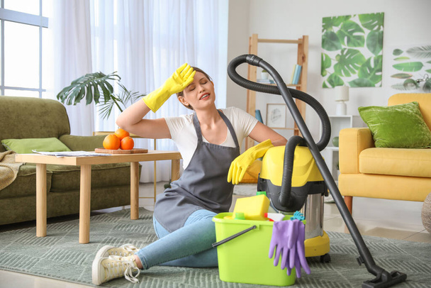 Young woman with vacuum cleaner and supplies at home - Photo, Image