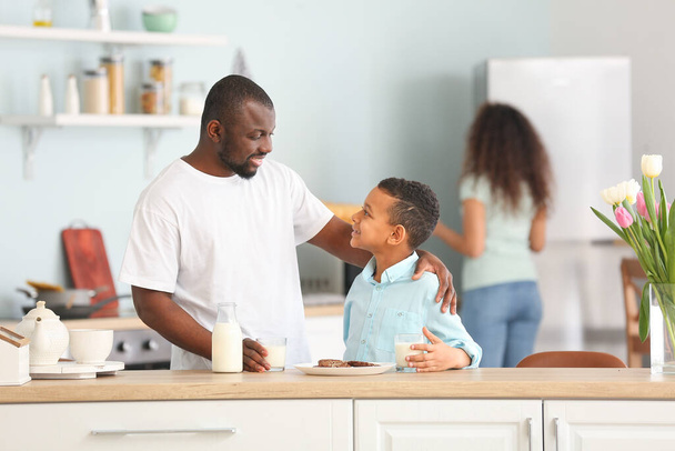 Uomo afro-americano e suo figlio che bevono latte in cucina
 - Foto, immagini