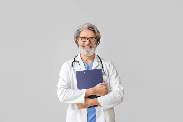 Portrait of senior male doctor on grey background - Photo, Image