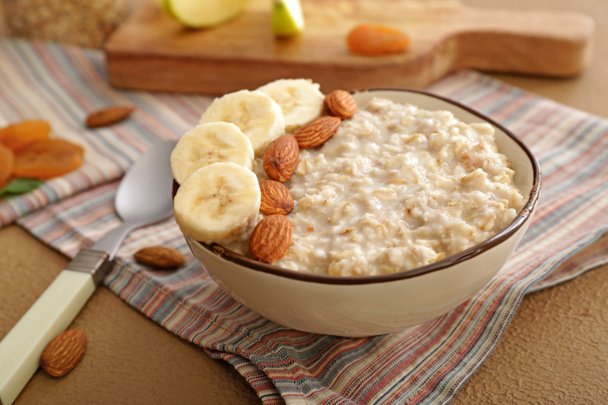 Bowl with tasty sweet oatmeal on table - Photo, Image