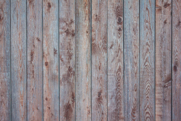 Fa kerítés, függőleges csíkok. Fa csomókkal, természetes minta. Barna és kék árnyalatok, nappal. - Fotó, kép