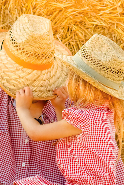 Father with a child playing near a haystack ranch on the field. Happy family have a rest. - 写真・画像