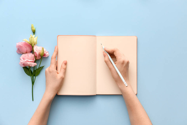 Woman writing something in notebook on color background - Photo, Image