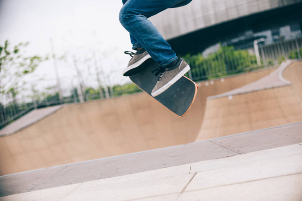 Female skateboarder jumping at skate park ramp - Fotó, kép