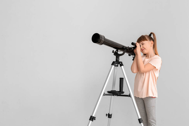 Cute little girl with telescope on light background - Photo, Image