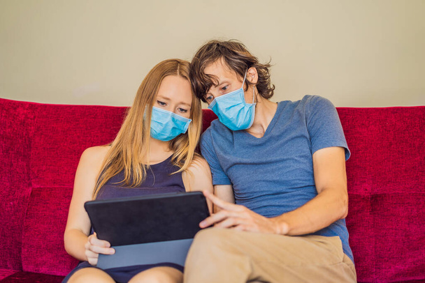 Man and woman are sitting in quarantine, sitting at home and looking at gadgets. Coronavirus, epidemic, quarantine - Fotografie, Obrázek