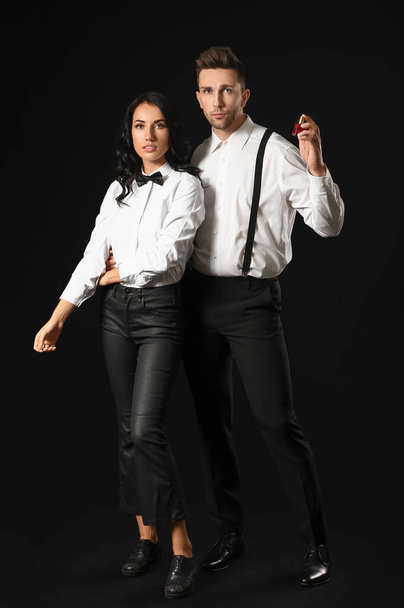 Stilvolles junges Paar mit Parfüm auf dunklem Hintergrund - Foto, Bild