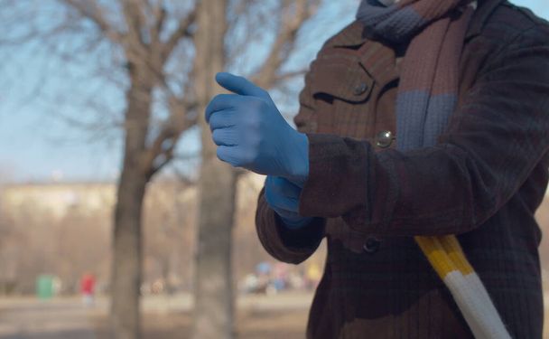Sluit de handen van een jongeman die buiten in de stad beschermende handschoenen aantrekt. Bescherm jezelf en je geliefden. Covid-19 pandemie - Foto, afbeelding