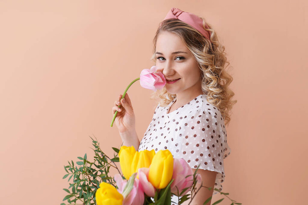 Beautiful young woman with bouquet of flowers on color background - Fotó, kép