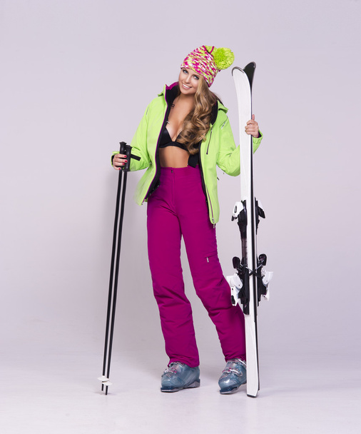 Retrato de mujer joven con ropa de abrigo sosteniendo esquís
 - Foto, Imagen