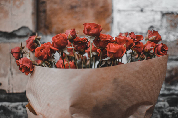 Red roses in a vase wrapped in paper - Fotó, kép