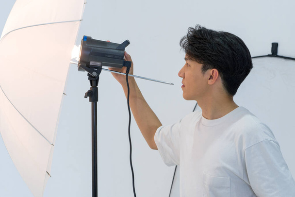 Asyalı fotoğrafçılar stüdyoda manken çekmek için ışıkların parlaklığını ayarlıyorlar.. - Fotoğraf, Görsel