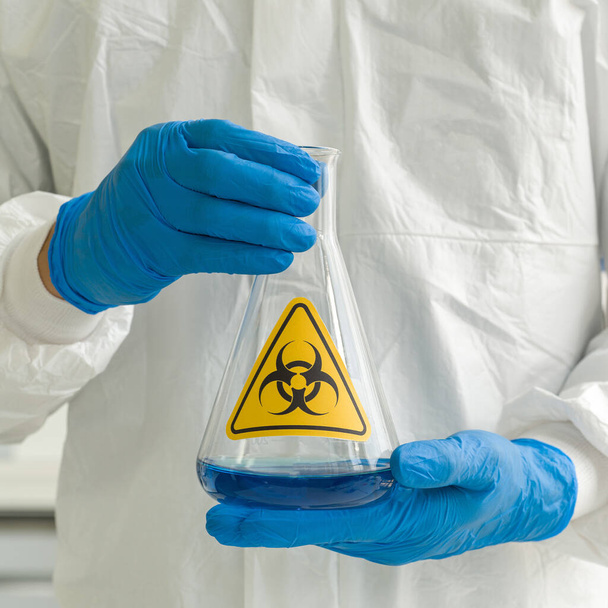 Erlenmeyerova baňka obsahuje modré kapalné chemikálie v rukou odborníků. - Fotografie, Obrázek
