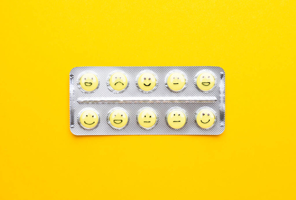 Blister pack and pills with drawn faces on color background - Photo, image