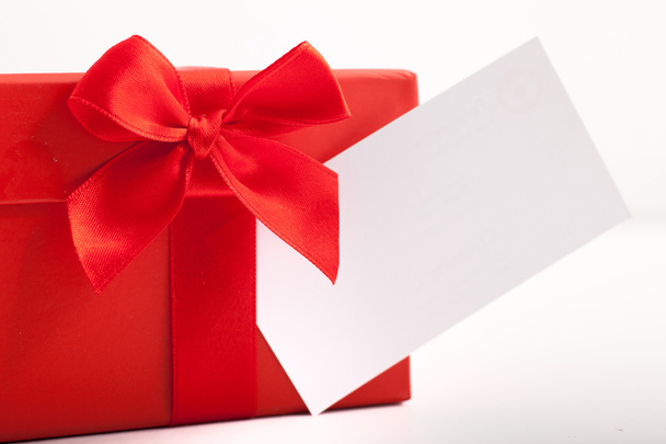 Decorative red Christmas gift tied with a ribbon and bow with a blank white gift tag for your seasonal greeting or message - Φωτογραφία, εικόνα
