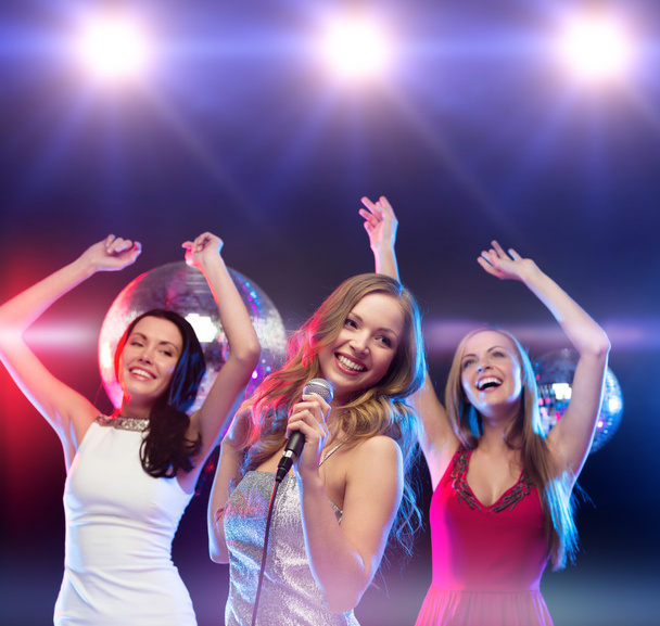 Three smiling women dancing and singing karaoke - Zdjęcie, obraz