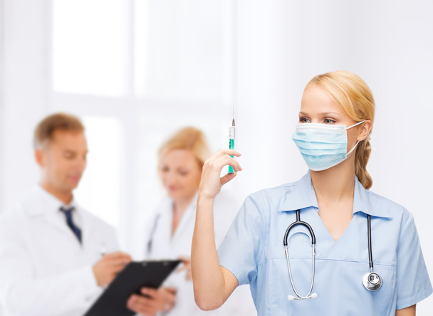 Female doctor or nurse in mask holding syringe - Фото, изображение