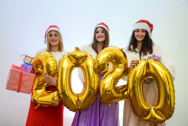 Trois femmes joyul avec ballon à air doré posant dans des robes de soirée élégantes. Nouvel an célébration
 - Photo, image