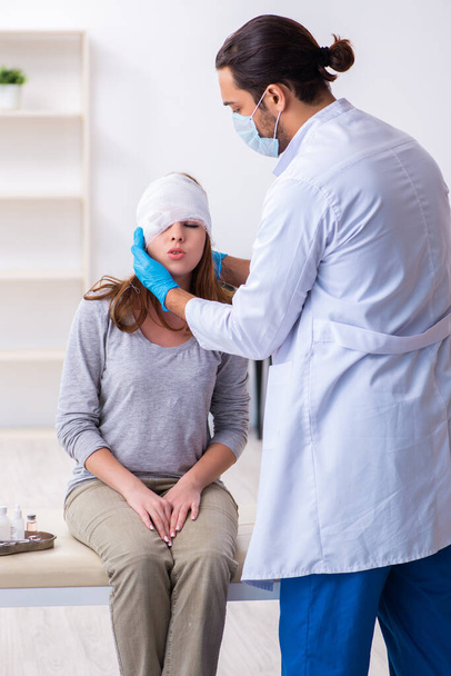 Young head injured woman visiting young male doctor - Foto, Imagen