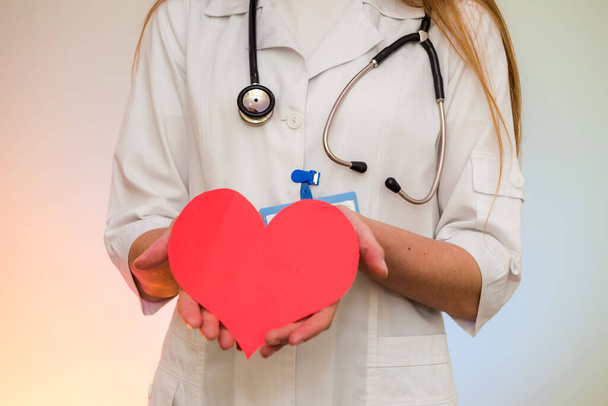 Az orvos vörös szívet tart. Kardiológus szív alakú kezekkel közelről - Fotó, kép