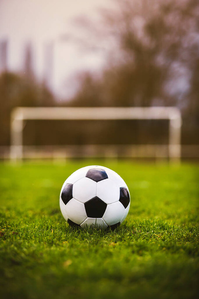 Klassieke voetbal bij zonsondergang met typische zwart-wit patroon, geplaatst op stadion grasmat. Traditionele voetbal bal op het groene gras gazon met kopieerruimte. - Foto, afbeelding
