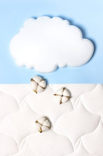 White air cloud, cotton flowers on a comfortable mattress texture background and blue background top view. White texture of mattress bedding background. Healthy sleep concept, comfortable bed. - Photo, Image