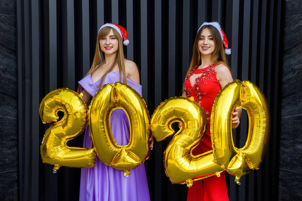 Πορτρέτο δύο όμορφων κοριτσιών την παραμονή της Πρωτοχρονιάς φορώντας κομψά βραδινά φορέματα - Φωτογραφία, εικόνα