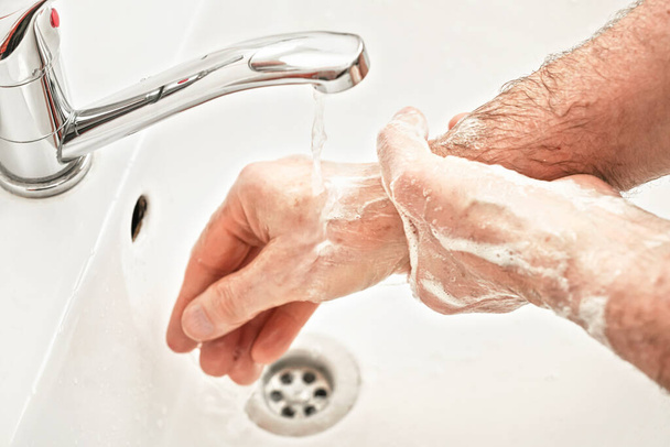 Senior elderly man his hands and wrist with soap under tap water faucet, detail photo. Can be used as hygiene illustration concept during ncov coronavirus / covid-19 outbreak prevention - Foto, afbeelding