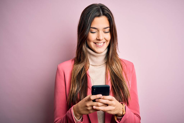 Молодая красивая девушка разговаривает с помощью смартфона на белом фоне с счастливым лицом стоя и улыбаясь с уверенной улыбкой показывая зубы
 - Фото, изображение