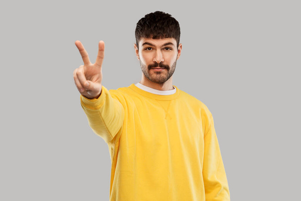 young man showing peace over grey background - Fotoğraf, Görsel