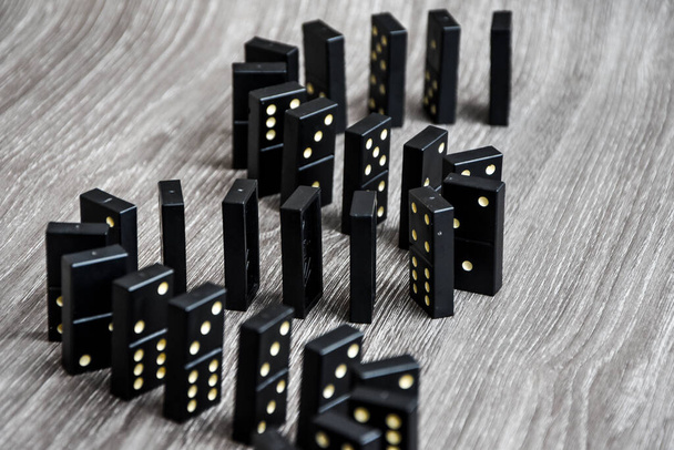 dominó negro en un soporte de mesa de madera ligera en una fila, enfoque selectivo, dominó negro viejo, vintage sobre un fondo de cartón. El concepto del juego dominó
 - Foto, Imagen