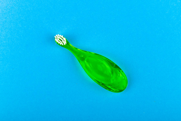 Зелена дитяча зубна щітка. на синьому фоні. Місце для напису. Чищення зубів дитині
 - Фото, зображення