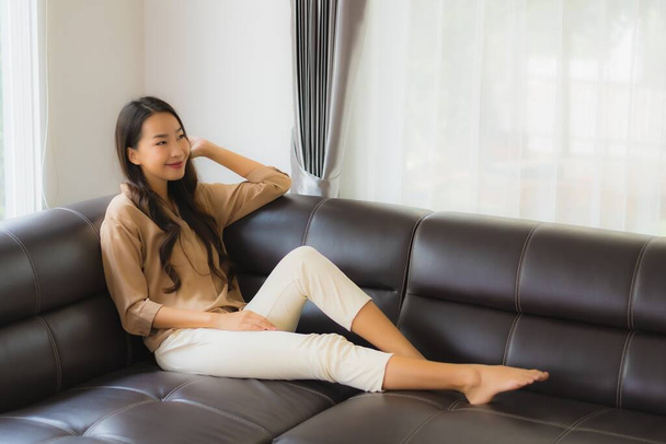Güzel bir Asyalı kadın portresi. Mutlu bir gülümseme. Oturma odasındaki kanepede rahatla. - Fotoğraf, Görsel