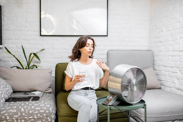 Femme se refroidissant avec un ventilateur à la maison
 - Photo, image