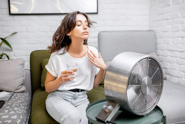 Frau kühlt sich zu Hause mit Ventilator ab - Foto, Bild