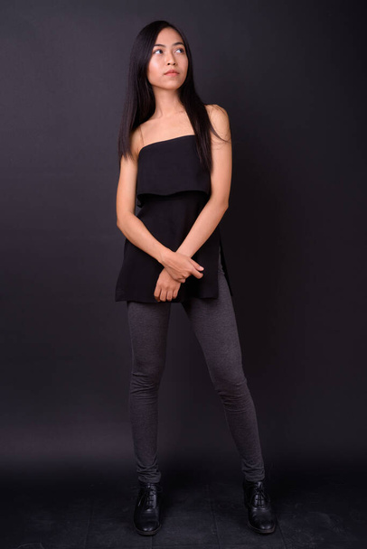 Studio shot of young beautiful Asian woman against black background - Photo, image