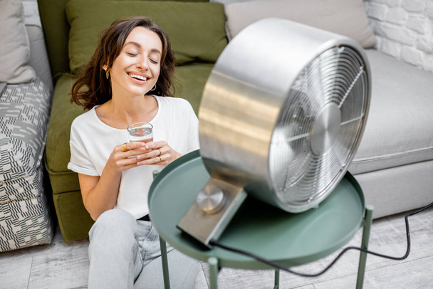 Mulher esfriando-se com um ventilador em casa
 - Foto, Imagem