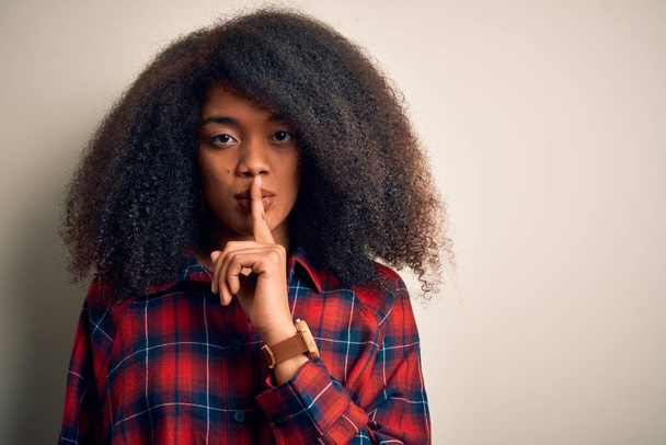 Nuori kaunis afrikkalainen amerikkalainen nainen yllään rento paita yli eristetty tausta pyytää olla hiljaa sormi huulilla. Hiljaisuus ja salainen käsite
. - Valokuva, kuva