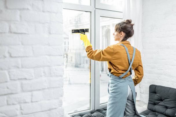 Femme au foyer laver les fenêtres à la maison
 - Photo, image