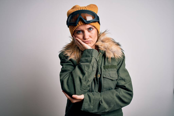 Nuori kaunis hiihtäjä nainen siniset silmät yllään lumi urheiluvaatteet ja hiihtolasit ajattelu näyttää väsynyt ja kyllästynyt masennus ongelmia ristissä kädet
. - Valokuva, kuva